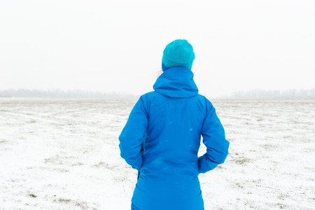 Woman in blue standing in a snowy fieldの写真素材