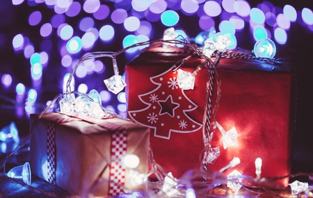 Christmas gift boxes with glowing garland and blue bokeh lightsの写真素材
