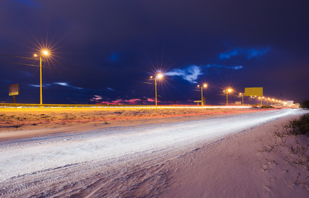 Winter snowy highway at night shined with lampsの写真素材