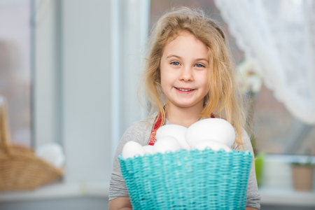 Little blonde girl holding basket with painted eggs. Easter day.の写真素材