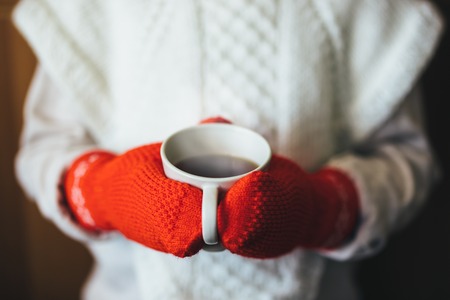 Cute blonde little girl holding hot steaming tea cup close up photoの写真素材