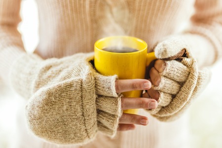 Woman holding hot steaming coffee cup close up photoの写真素材