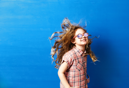 Happy child girl tourist in pink sunglasses at the blue wall. Travel and adventure conceptの写真素材