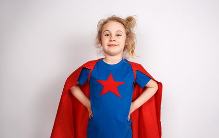 Six year blonde girl dressed like superhero having fun at home. White wall on backgroundの写真素材