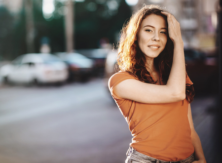 Summer outdoor porttrait of young pretty girl posing at sunset in cityの写真素材