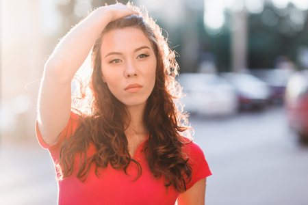 Summer outdoor porttrait of young pretty girl posing at sunset in cityの写真素材
