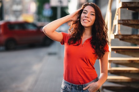Summer outdoor porttrait of young pretty girl posing at sunset in cityの写真素材