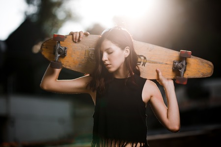 Urban fashionable girl with longboard posing outdoors in the city.の写真素材