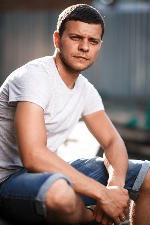 Outdoor portrait of a handsome young man in jeans and gray t-shirt.の写真素材
