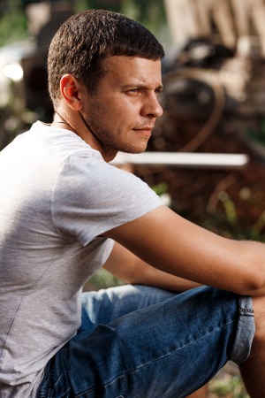Outdoor portrait of a handsome young man in jeans and gray t-shirt.