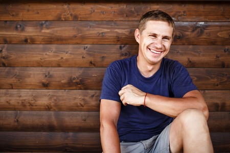 Young man sitting and relaxing on wooden deck outdoor.の写真素材