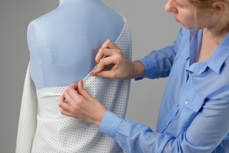 Fashion designer working with blue tailor dummy in her workshop.の写真素材