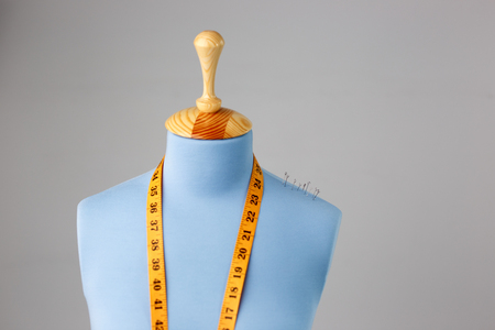 Blue tailor dummy with measuring tape alongside the wall.の写真素材