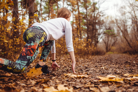 Concentrared young sporty woman is ready to run outdoors in the autumn parkの写真素材
