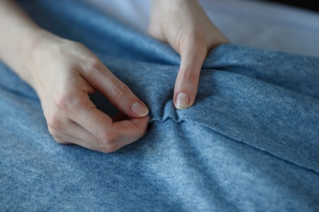 Closeup of skilled tailor hands marking and measuring fabric while making clothes.