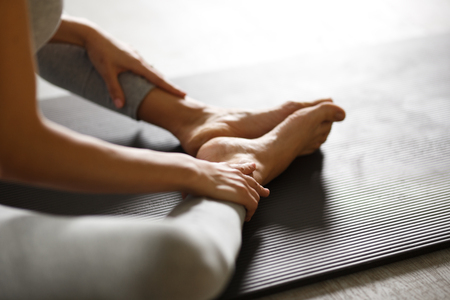 Young sporty woman doing yoga stretching exercise sitting in gym near bright windowsの写真素材
