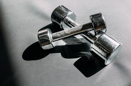 Chrome-plated dumbbells lying on a rubber floor in gymの写真素材
