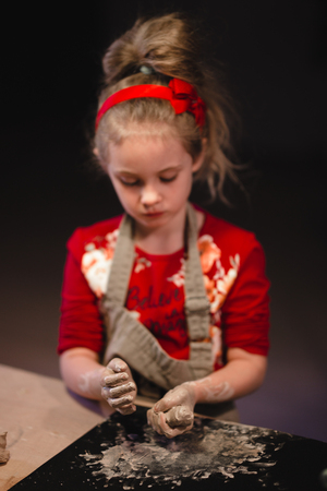 Young seven years old girl in pottery workshop creating a bowl from clay. Pottery workshop for kidsの写真素材