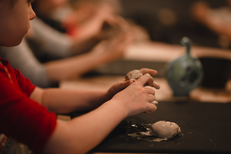 Young seven years old girl in pottery workshop creating a bowl from clay. Pottery workshop for kidsの写真素材