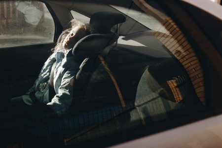 Seven-year charming girl sleeping in a childrens car seatの写真素材