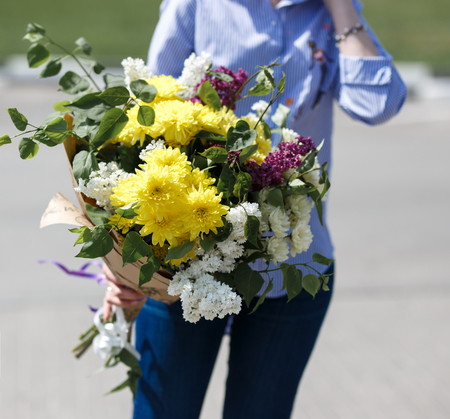 Young woman in blue cotton blouse and jeans holding a bouquetの写真素材