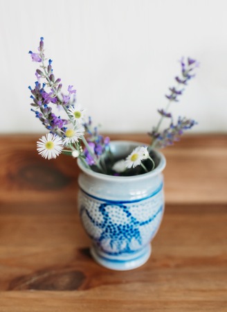 Small ceramic vase with lavender and chamomile on a wooden surfaceの写真素材
