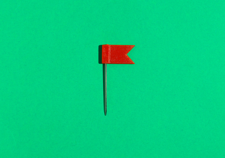 Red little flag pin on a green background. View from aboveの写真素材