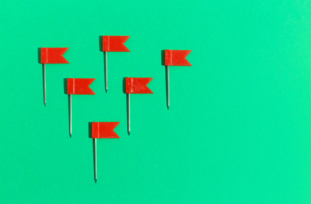 Red little flag pins on a green background. View from aboveの写真素材