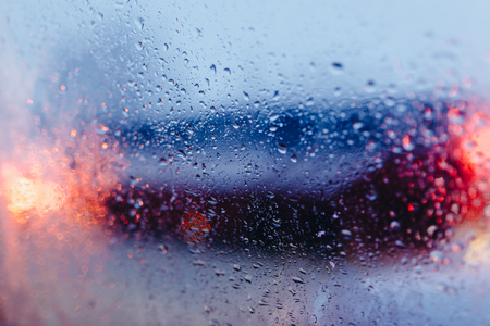 Night city road through windshield cars abstract background water drop on the glass lights and rainの写真素材