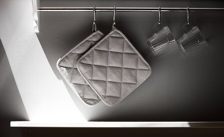 Part of the sunny kitchen with a gray wall. Shelf with glasses and railing with napkinsの写真素材