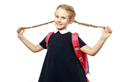 Cheerful 8 years old schoolgirl with backpack wearing uniform standing isolated over white...