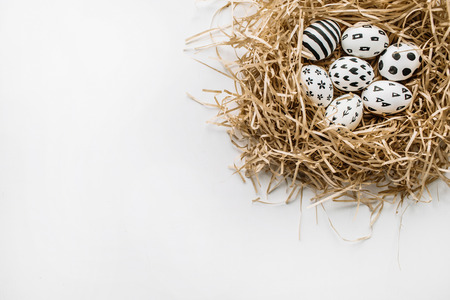Easter eggs in the nest painted in monochrome style isolated on white. Flat lay. Drops, flowers, hearts, stars, stripesの写真素材