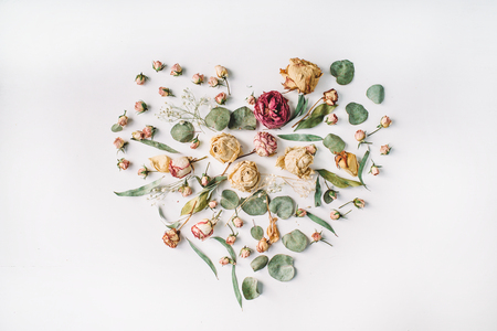 Heart made with beige roses and green leaves isolated on white background. Flat layの写真素材