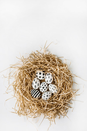 Easter eggs in the nest painted in monochrome style isolated on white. Flat lay. Drops, flowers, hearts, stars, stripesの写真素材