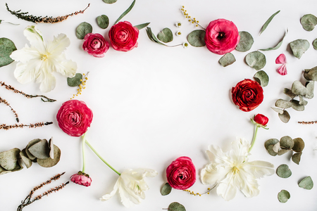 wreath frame with pink and red roses or ranunculus, white tulips and green leaves on white background. Flat lay, top viewの写真素材