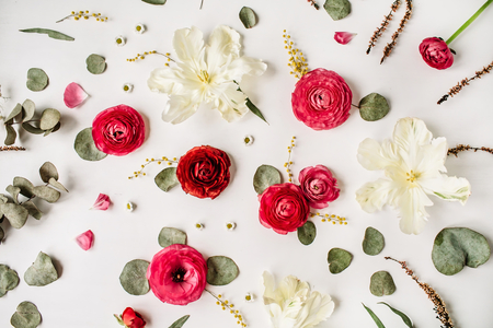 Pattern with pink and red roses or ranunculus, white tulips and green leaves on white background. Flat lay, top viewの写真素材