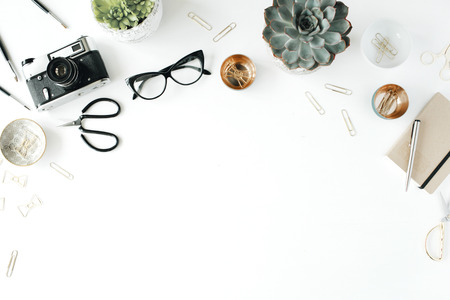 feminini desk workspace with succulent, retro camera, scissors, diary, glasses and golden clips on white background. flat lay, top viewの写真素材