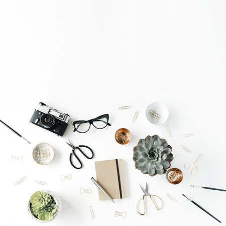 feminini desk workspace with succulent, retro camera, scissors, diary, glasses and golden clips on white background. flat lay, top viewの写真素材