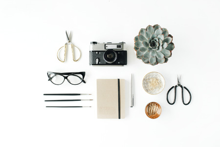 feminini desk workspace with succulent, retro camera, scissors, diary, glasses and golden clips on white background. flat lay, top viewの写真素材