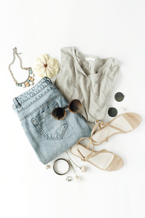 flat lay feminini clothes and accessories collage with shirt, jeans shorts, sunglasses, bracelet, sandals, earrings on white background.の写真素材
