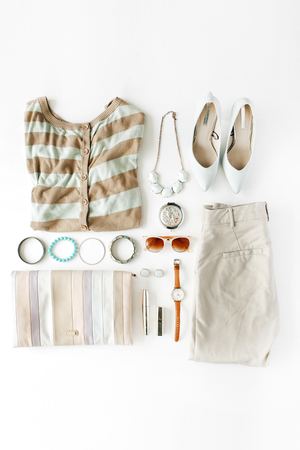 flat lay feminini clothes and accessories collage with cardigan, trousers, sunglasses, watch, bracelet, lipstick, mint high heel shoes, earrings and purse on white background.の写真素材