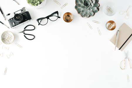 feminini desk workspace with succulent, retro camera, scissors, diary, glasses and golden clips on white background. flat lay, top viewの写真素材
