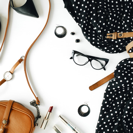 flat lay feminine clothes and accessories collage with black dress, glasses, high heel shoes, purse, watch, mascara, lipstick, earrings on white background.の写真素材