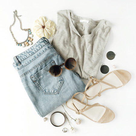 flat lay feminine clothes and accessories collage with shirt, jeans shorts, sunglasses, bracelet, sandals, earrings on white background.の写真素材