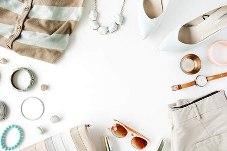 flat lay feminine clothes and accessories collage with cardigan, trousers, sunglasses, watch, bracelet, lipstick, mint high heel shoes, earrings and purse on white background.