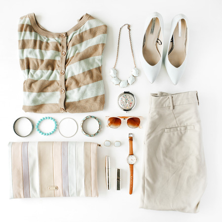 flat lay feminine clothes and accessories collage with cardigan, trousers, sunglasses, watch, bracelet, lipstick, mint high heel shoes, earrings and purse on white background.の写真素材