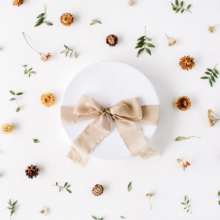 white gift cardboard box with brown bow on white background with floral composition. flat lat, top viewの写真素材
