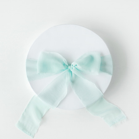white gift cardboard box with blue bow on white background. flat lat, top viewの写真素材