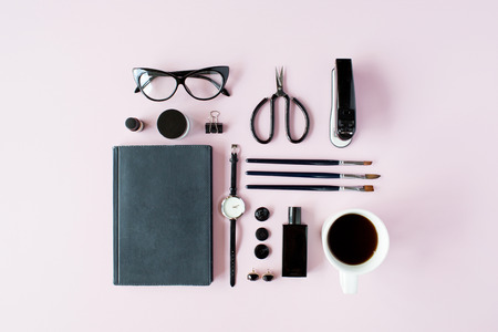 Flat lay, top view black style office table desk. feminine working supplies: glasses, diary, watches, perfume, brushes, scissors, coffee on pink background.の写真素材