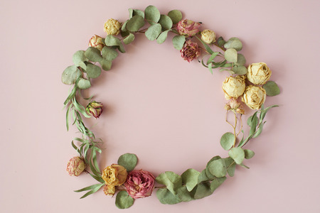 round frame wreath pattern with roses, pink flower buds, eucalyptus branches and leaves on pink background. flat lay, top viewの写真素材